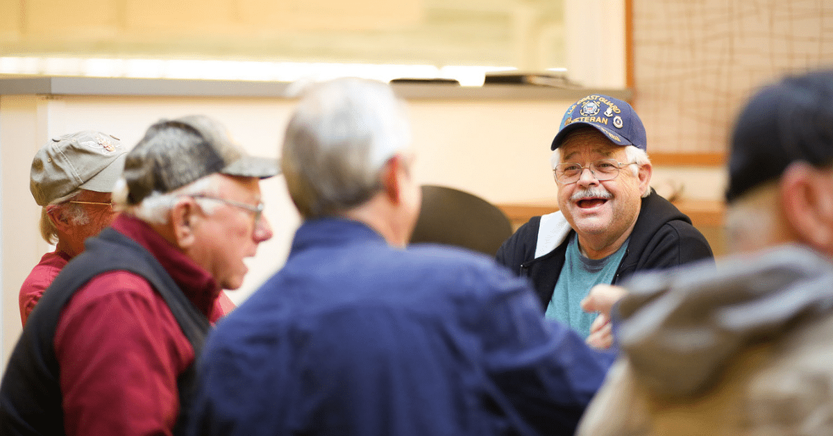 A group of men stands in a circle, talking and laughing